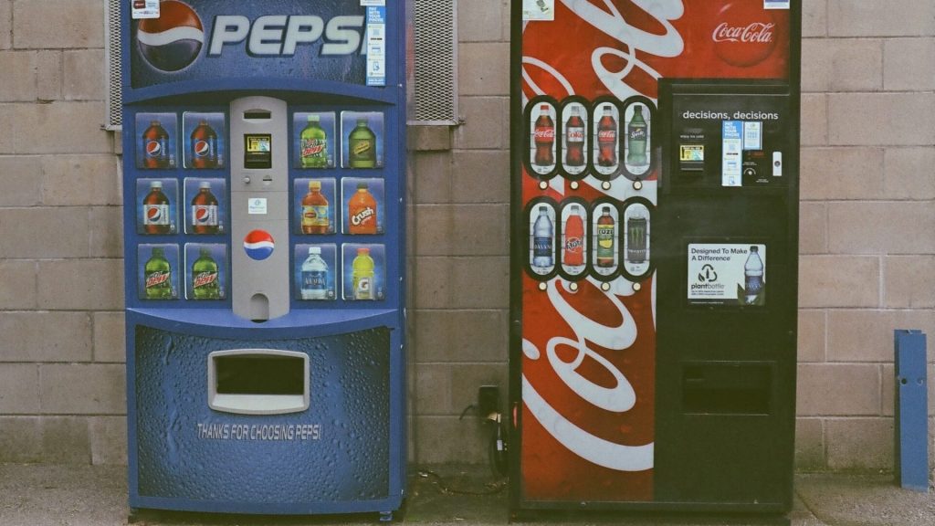 Dos máquinas expendedoras: Una con la marca Coca-Cola y la otra con Pepsi