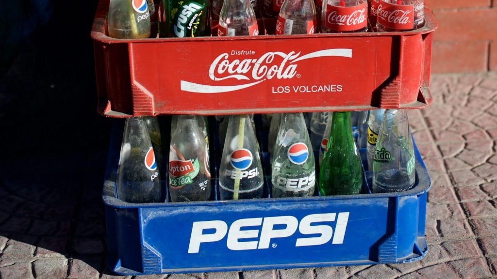 Dos cajas de botellas: Una con botellas de Coca-Cola y otra con botellas de Pepsi